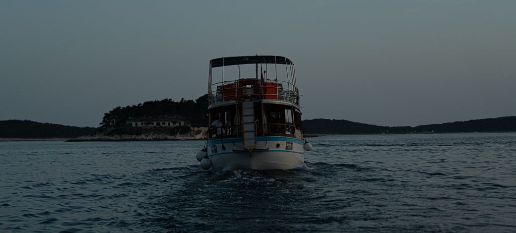 A small ferry crossing a grey sea with an island behind it